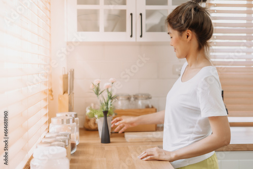 Asian woman rearrange equipments items and cleaning the kitchen.