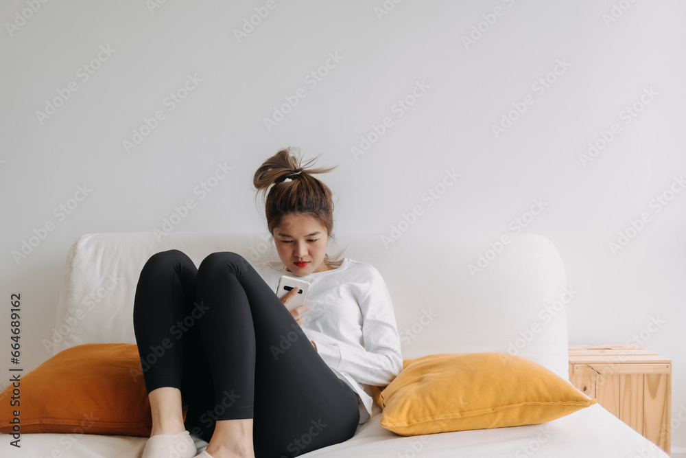 Asian woman using smartphone relaxed on sofa in cold day. Asian woman using smartphone relaxed on sofa in cold day.
