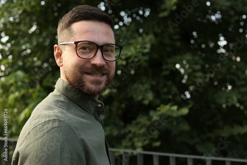 Portrait of handsome bearded man in glasses outdoors, space for text