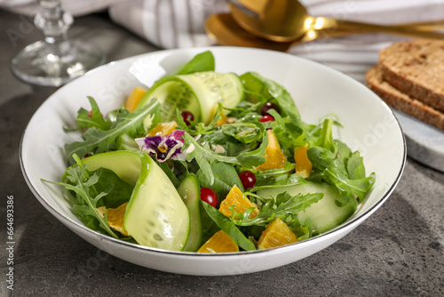 Delicious salad with cucumber and orange slices on gray table