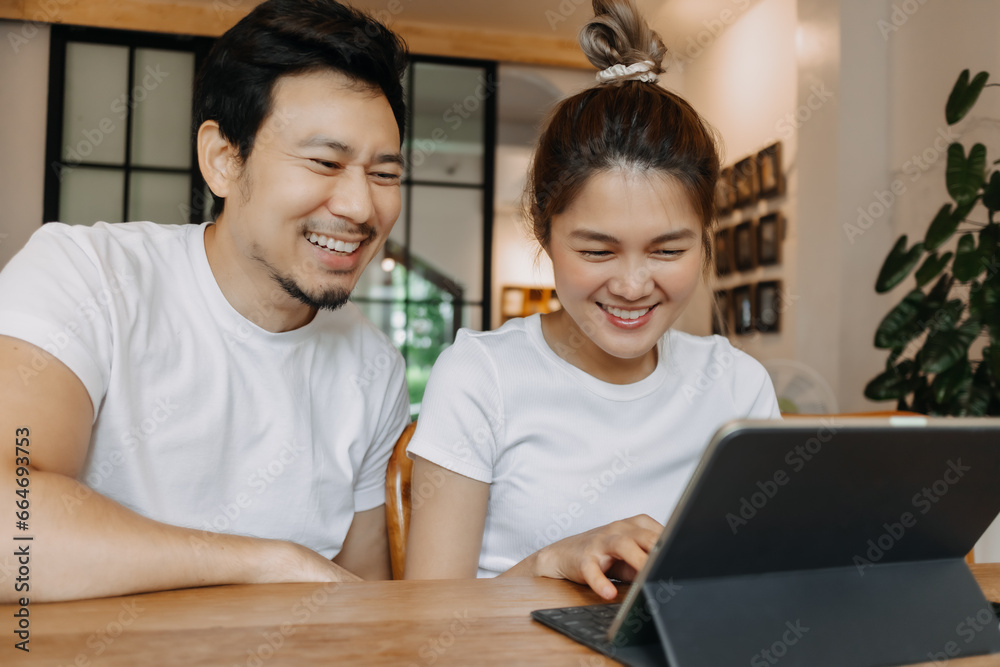 Happy laughing asian couple watching computer tablet together in the cafe. Happy laughing asian couple watching computer tablet together in the cafe.