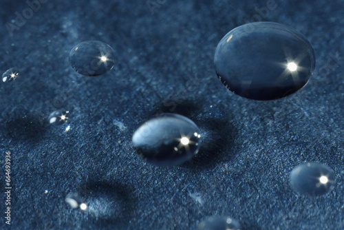 Water drops on glass against dark gray textured background. Macro photography