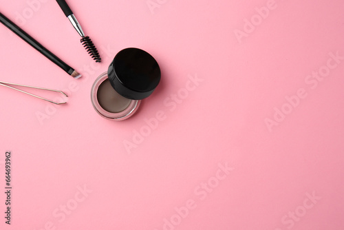 Eyebrow pomade with henna effect and professional tools on pink background, flat lay. Space for text