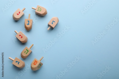 Wooden dreidels on light blue background  flat lay with space for text. Traditional Hanukkah game
