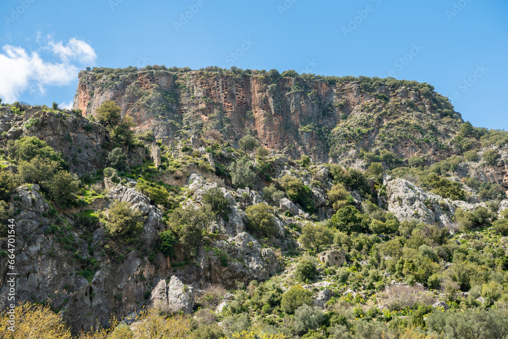 Landscape at Pinara ancient site in Mugla province of Turkey with a crag honeycombed with rock-cut tombs. Pinara was a large city of ancient Lycia.