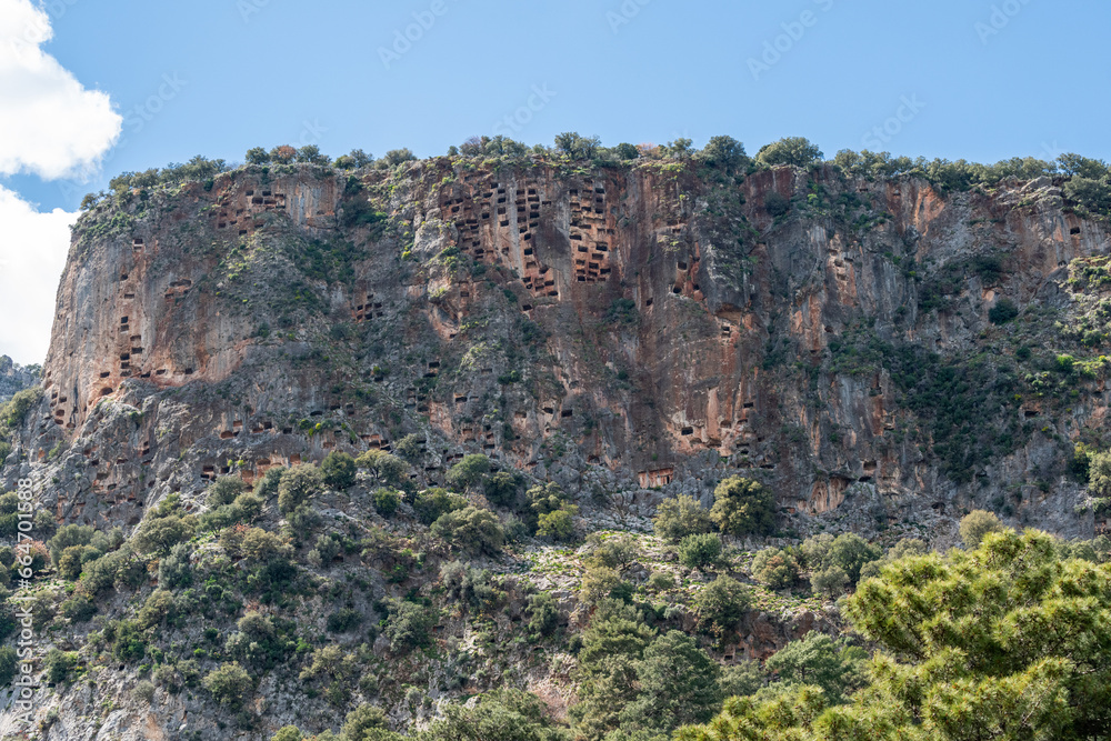Crag honeycombed with rock-cut tombs towering over Pinara ancient site in Mugla province of Turkey. Pinara was a large city of ancient Lycia.