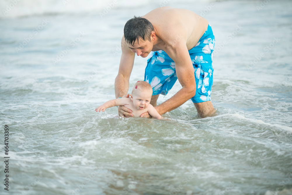 Father and baby swiming in the ocean. Dad and him Child together enjoying sunset. Loving single father hugs cute little son. Father and baby swiming in the ocean. Dad and him Child together enjoying sunset. Loving single father hugs cute little son.