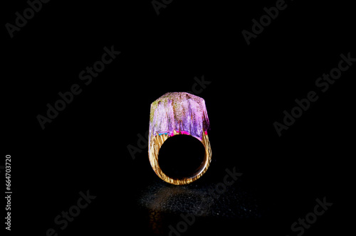 Photo of a women's wooden ring with epoxy resin on a black background. Present. Product for the site.