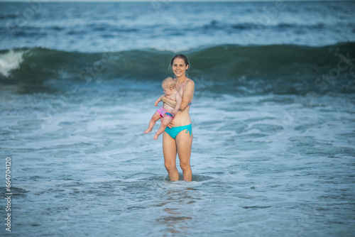 mother hugging her baby boy at the ocean wave. Concept of union and tender connection between a young mama and his lovely child.