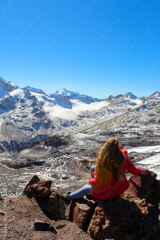 The girl with bright red hair overlooking the mountains with glaciers