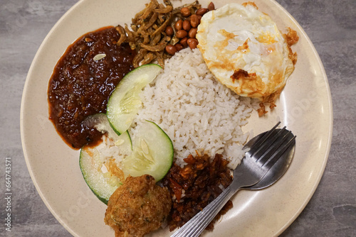 Nasi lemak, a Malay style complete meal of fragrant rice cooked in coconut milk and eaten together with chili paste, fried chicken, hard boiled egg, anchovies and cucumber photo