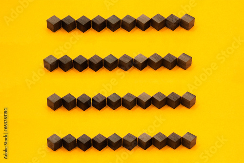 茶色いウッドキューブを直線に4列並べた黄色い背景の装飾素材 photo