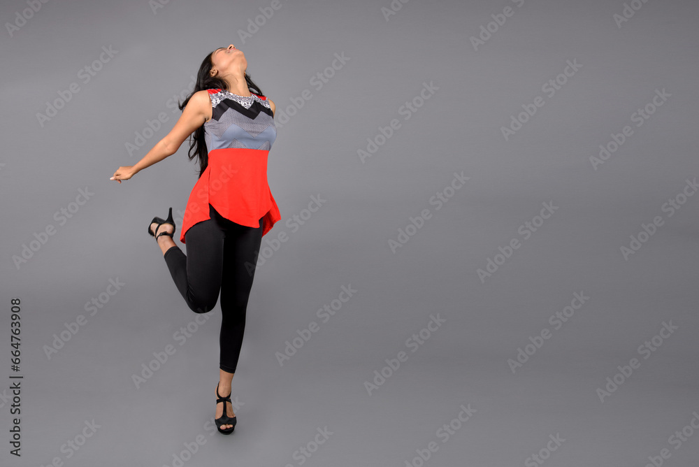 A cheerful young Indian female model jumping in joy in casual wear, wearing red and grey designer top and black jeans. Female model, Fashion Portrait, Advertisement shoot. A cheerful young Indian female model jumping in joy in casual wear, wearing red and grey designer top and black jeans. Female model, Fashion Portrait, Advertisement shoot.