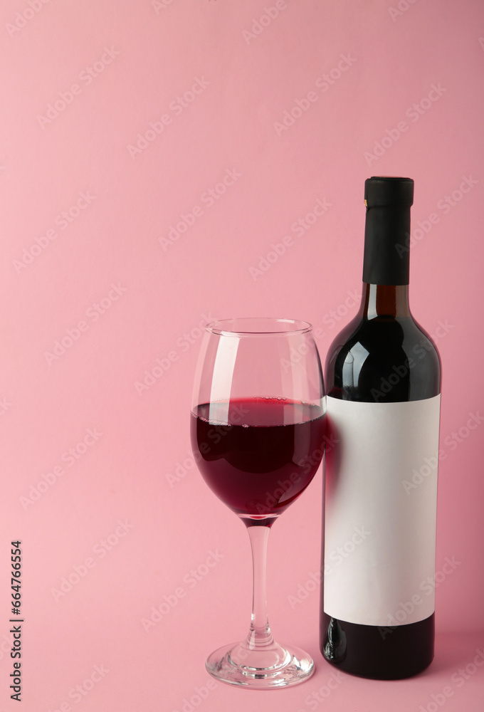 Wine bottle and wine glass on pink background. Vertical photo Wine bottle and wine glass on pink background. Vertical photo