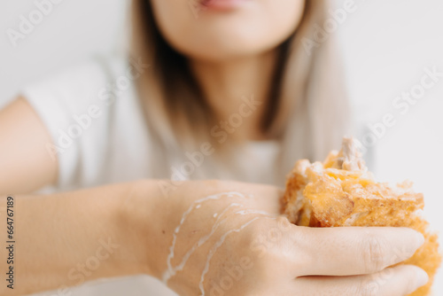 Close up of woman messy hand with white sauce while eating sandwich.