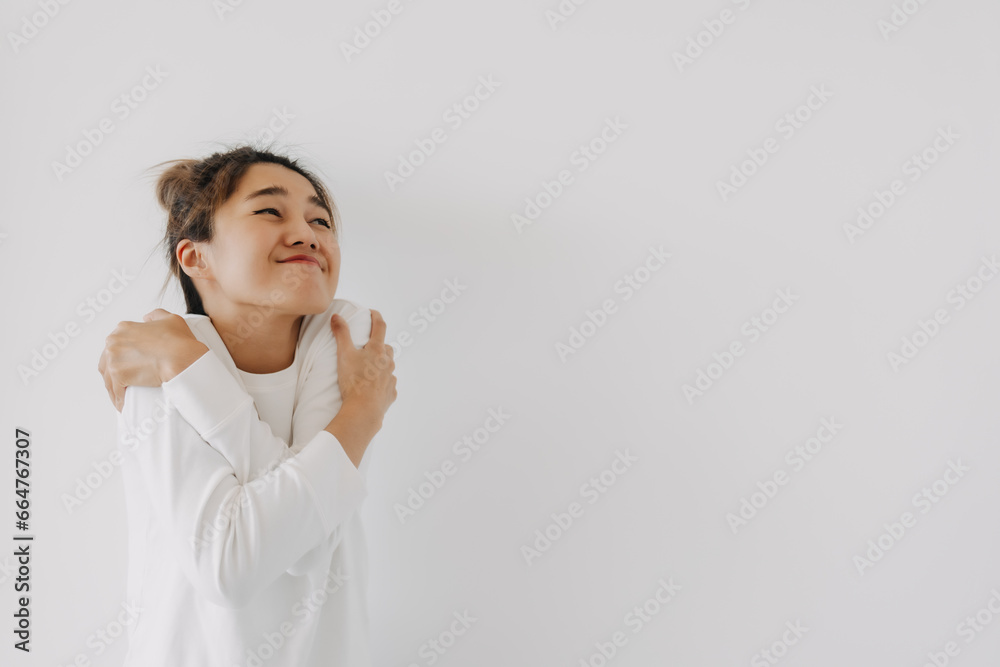 Asian Thai woman happy smiling, bun hair wear white sweater, cute cuddle and hugging herself tightly, loving yourself isolated over white background. Asian Thai woman happy smiling, bun hair wear white sweater, cute cuddle and hugging herself tightly, loving yourself isolated over white background.