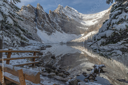 Obraz na płótnie Snow covered mountain peaks in the Rocky Mountains bathed in morning sunlight are mirrored in the placid waters of a lake. w salonie