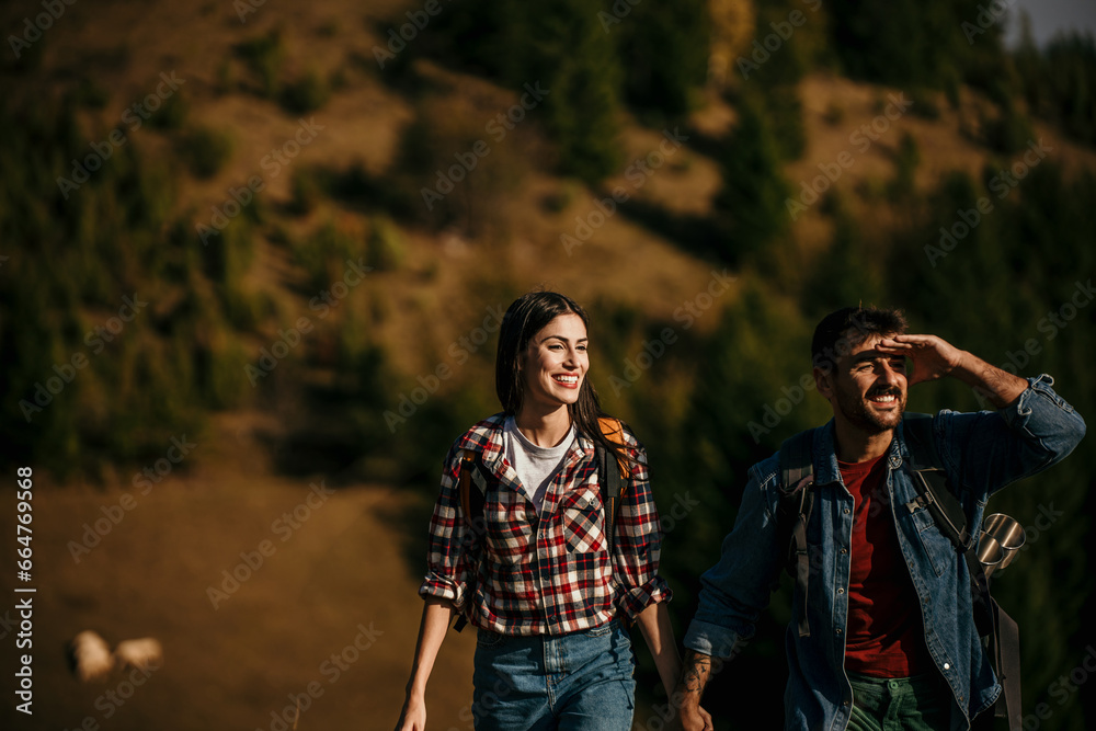A diverse couple joyfully hiking on a sunny day, with backpacks in tow