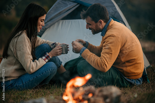 Sweet moments of a loving couple bonding by the campfire with a stunning lake scene