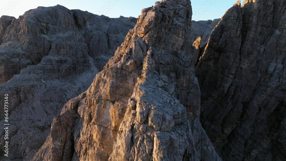 Dynamic aerial tracking shot over the Dolomites' rock formations, capturing the moment when the first sun rays touch the mountain summits. Dynamic aerial tracking shot over the Dolomites' rock formations, capturing the moment when the first sun rays touch the mountain summits.