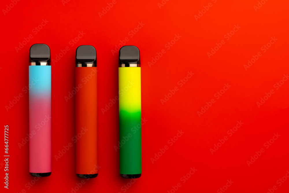 Disposable electronic cigarettes on red background close up Disposable electronic cigarettes on red background close up
