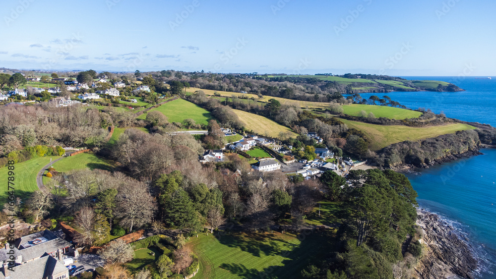 Obraz premium View of a village next to the rocky coastline of Helston passage on a sunny afternoon