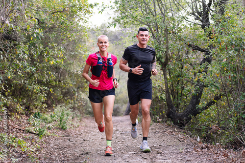 couple practicing trail running in the forest  concept of sport in nature and healthy lifestyle  copy space for text