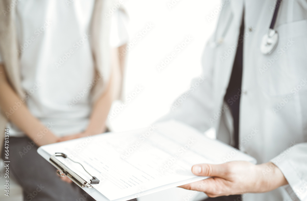 Doctor and child patient. The physician is holding clipboard with medication history records form near a boy. The concept of ideal health in medicine Doctor and child patient. The physician is holding clipboard with medication history records form near a boy. The concept of ideal health in medicine