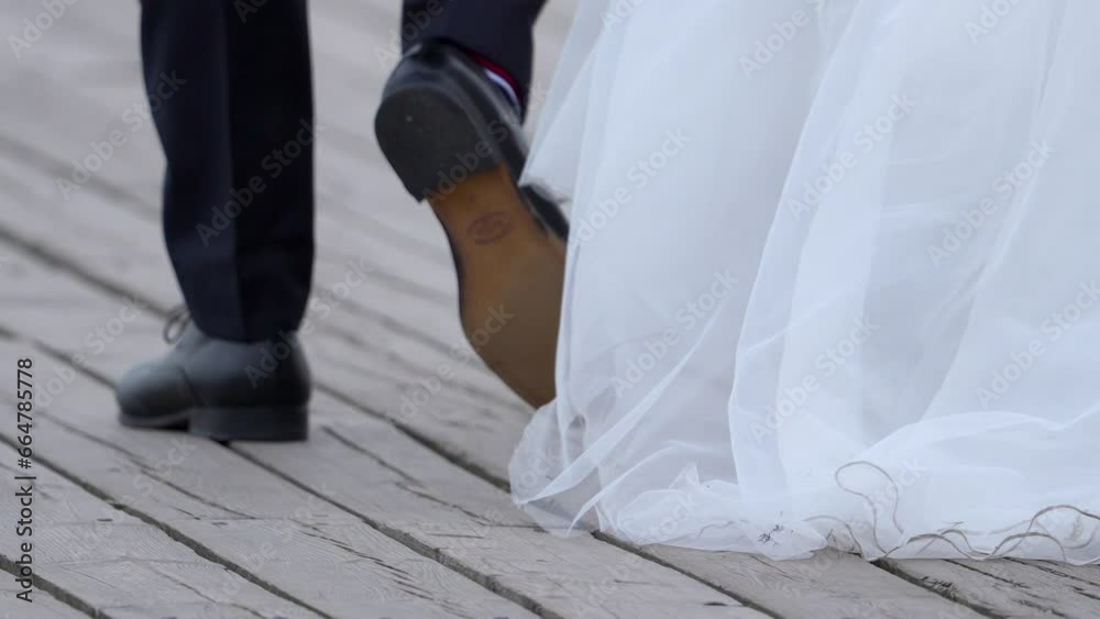 A man in a black suit and shoes is walking on the pier beside his bride to be A man in a black suit and shoes is walking on the pier beside his bride to be