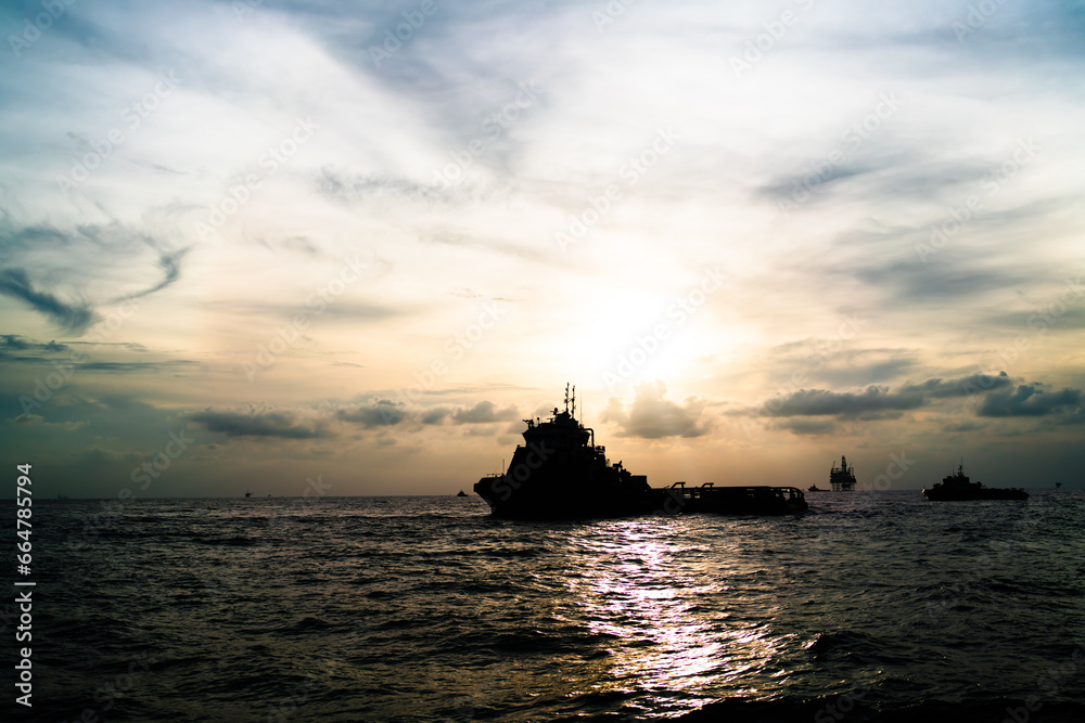 Fototapeta premium Transport ship of offshore gas and oil drilling platform in petroleum industry at sunrise morning.