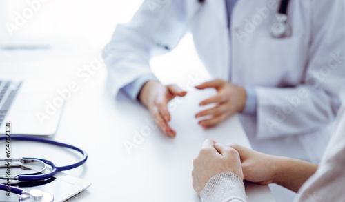 Stethoscope lying on the tablet computer in front of a doctor and patient at the background . Medicine, healthcare, reasuring hands concept