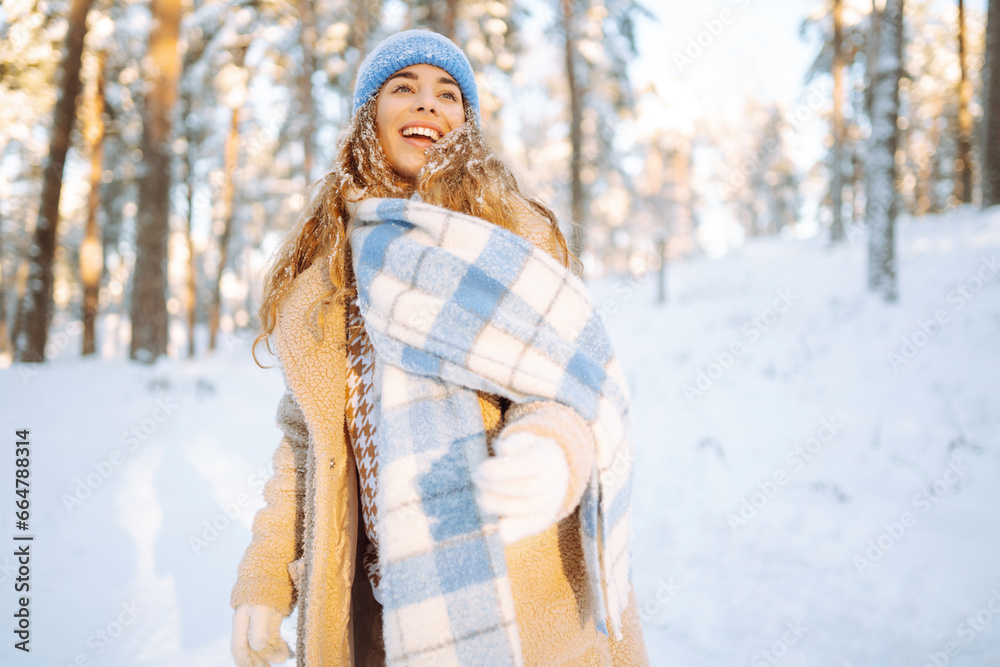 Smiling woman in a winter snow-covered park walks and plays with snow on a beautiful sunny day. Young fashionable woman in the winter forest. Walking concept, weekend. Smiling woman in a winter snow-covered park walks and plays with snow on a beautiful sunny day. Young fashionable woman in the winter forest. Walking concept, weekend.