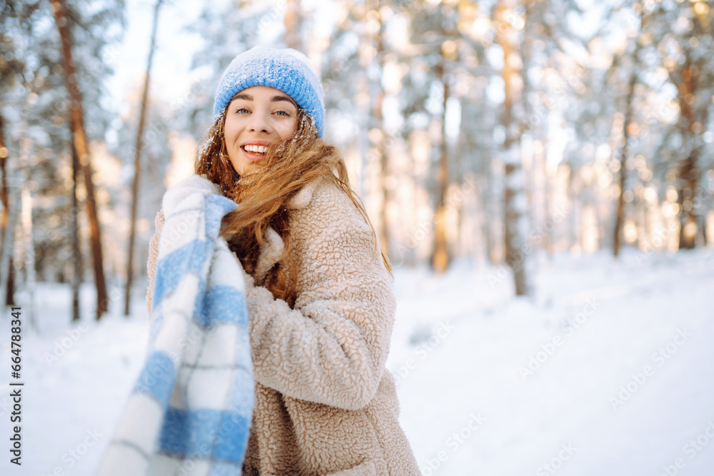 Smiling woman in a winter snow-covered park walks and plays with snow on a beautiful sunny day. Young fashionable woman in the winter forest. Walking concept, weekend. Smiling woman in a winter snow-covered park walks and plays with snow on a beautiful sunny day. Young fashionable woman in the winter forest. Walking concept, weekend.
