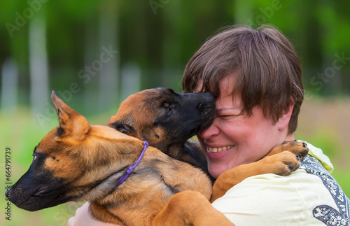 Laughing woman holding two Belgian Malinois puppies in her arms