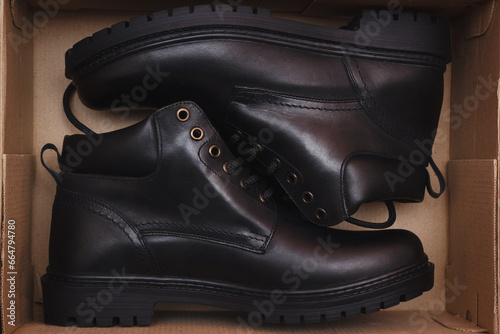 The leather boots in the box. A pair of the new classic black footwear purchased in shoes store. © Mediagfx