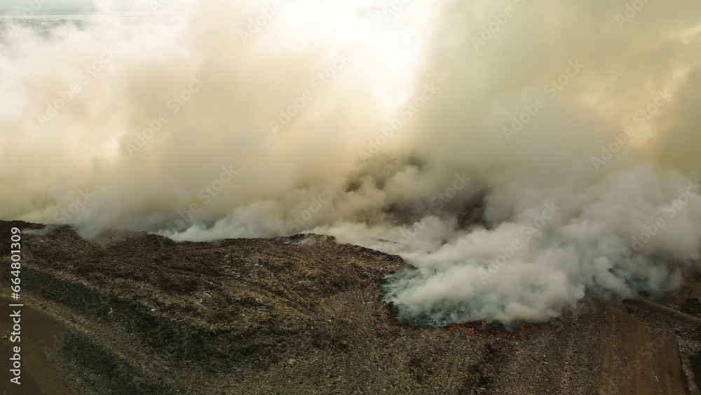 Aerial view of a catastrophic fire at a large landfill, plastic waste burning. Poisonous smoke rises into the sky and poisons the air. Environmental pollution, ecological disaster.