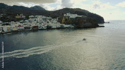 Boat cruising with Nisyros in the background on a cloudy day photo