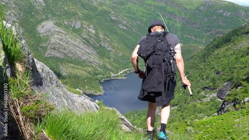 Man complete mountain fishing trip and proceeds downhill towards Bergsdalen Norway while holding fishing rod in hs hand photo