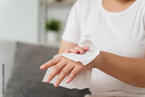 Woman wipes cleaning her hand with a tissue paper towel. Healthcare and medical concept.
