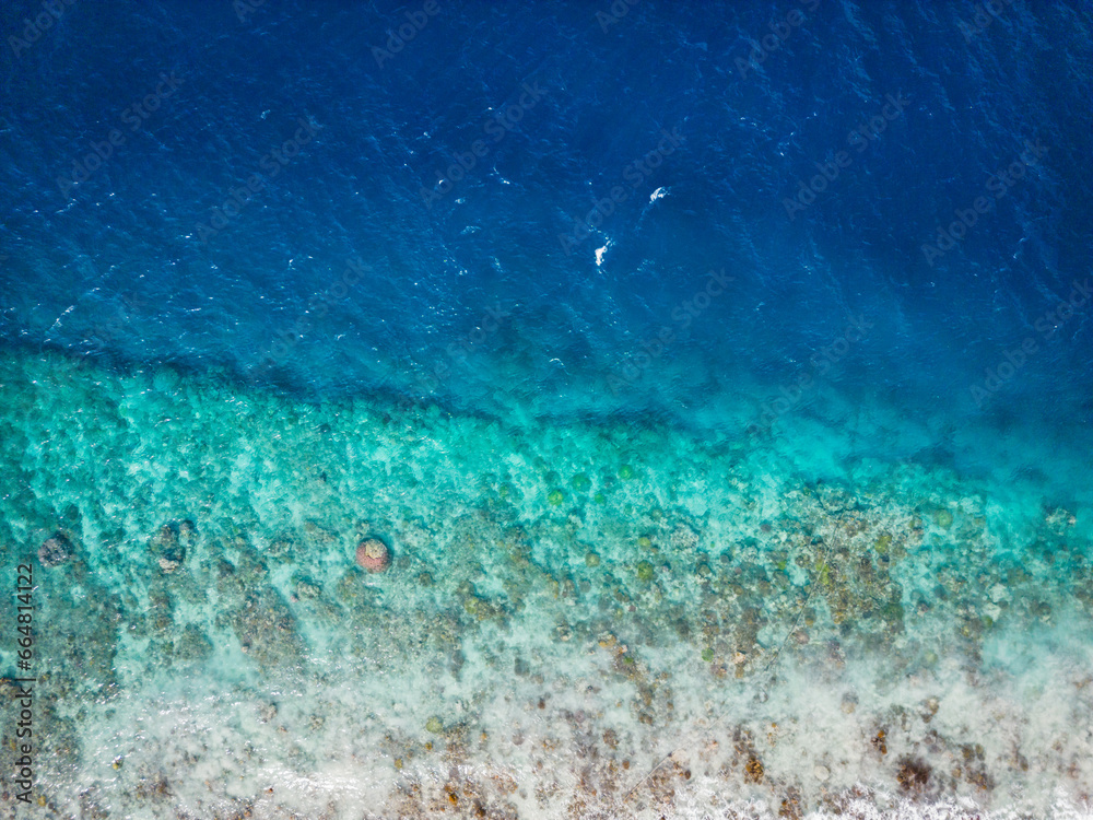 Fototapeta premium Beautiful costaline with differend shade of ocean colour at Gili Island in Lombok, Indonesia. Vertical aerial view of seashore