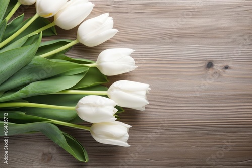 White tulips on wood table.
