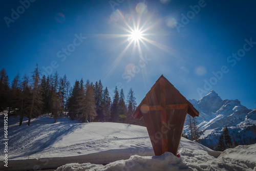 Wooden crucifix at the Staulanza Dolomite pass. Sun over Mount Civetta landscape in the background. Val di Zoldo, Belluno, Italy photo