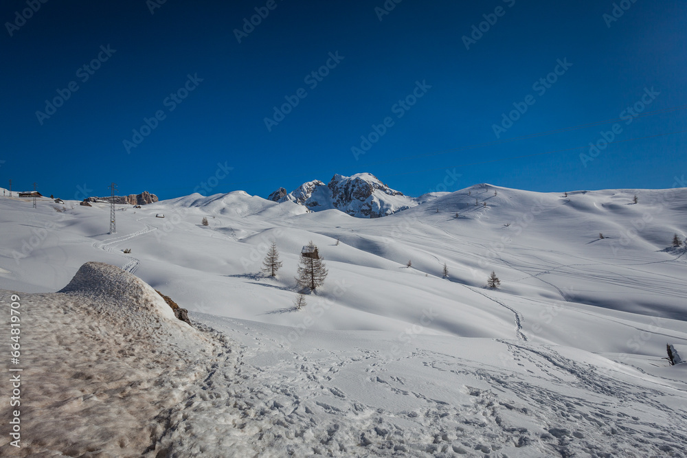 Traces of skiers and snowboarders on white snowy meadows of Giau Pass. In the background the majestic walls of the Mount Cernera. Giau Pass, Dolomites, Italy
