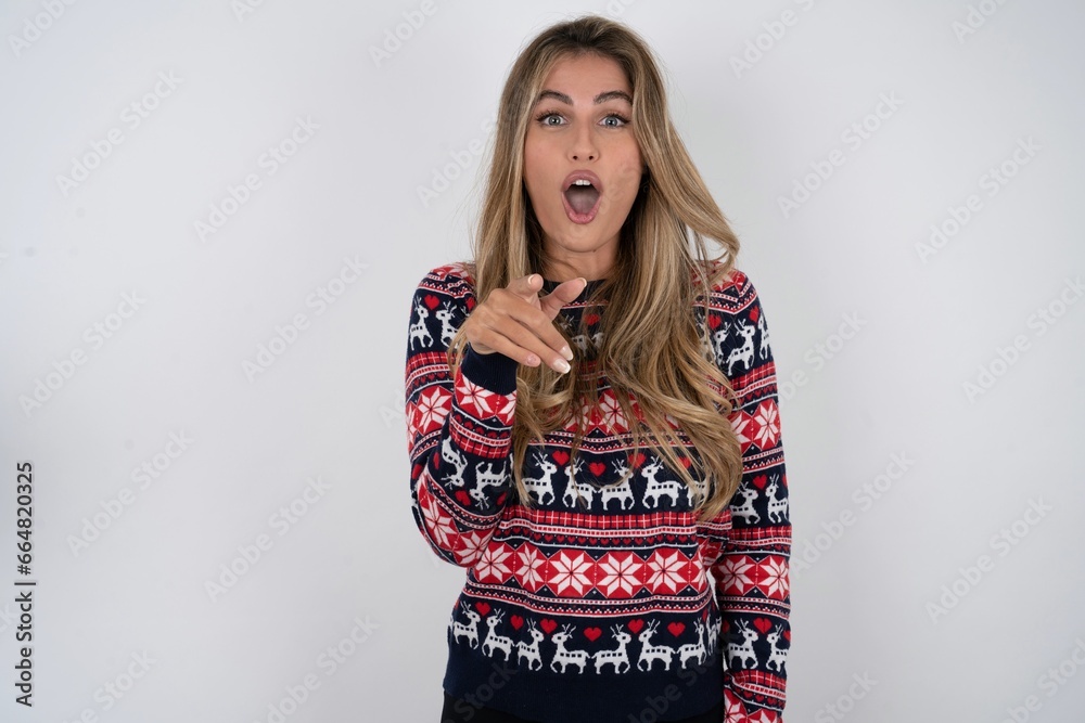 Shocked Young beautiful woman points at you with stunned expression