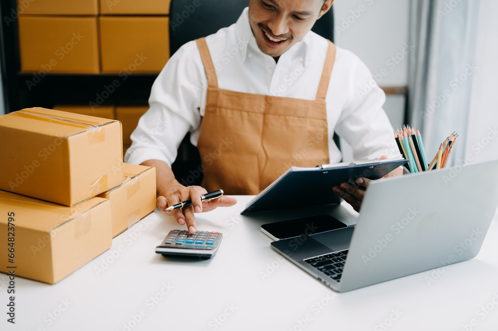 ฺusiness owner man prepare parcel box and standing check online orders for deliver to customer on tablet, laptop Shopping Online concept... ฺusiness owner man prepare parcel box and standing check online orders for deliver to customer on tablet, laptop Shopping Online concept...