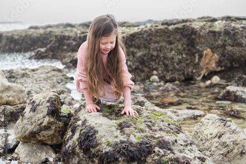 Child rock pooling at Hope Gap Beach between Seaford and Eastbourne, East Sussex. Beach and sea in foggy morning