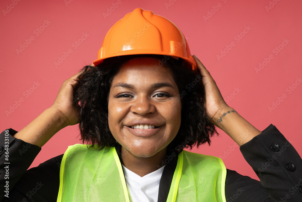 Smiling curly woman in helmet on pink background Smiling curly woman in helmet on pink background