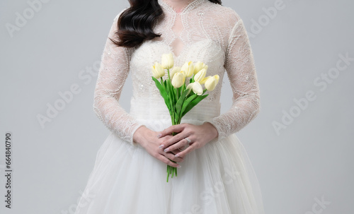 Asian female bride on gray background Close up image with flowers holding hands