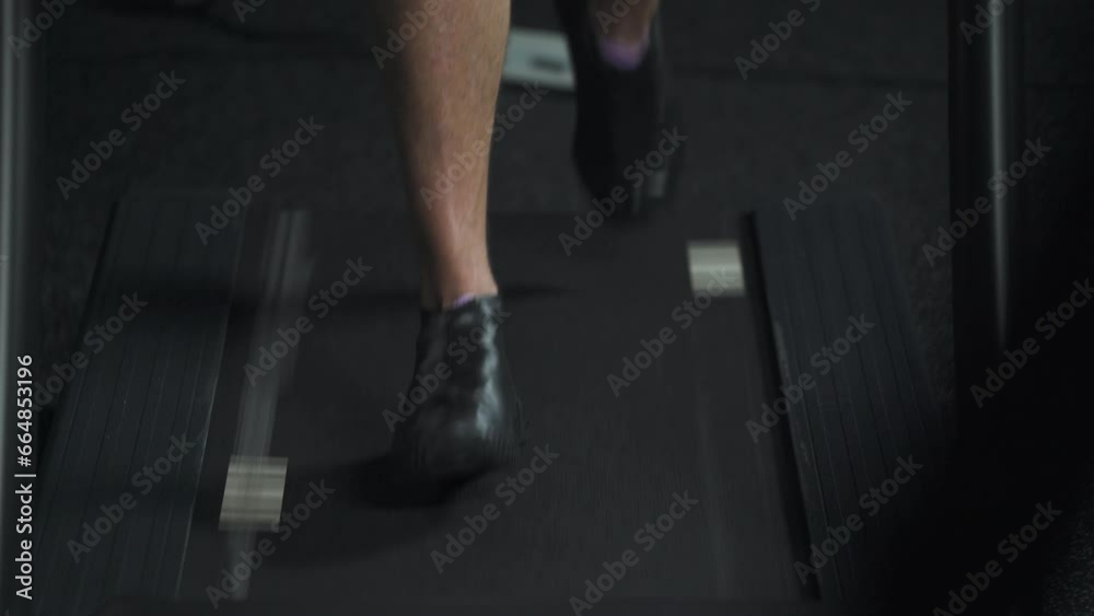 Sporty man running on a treadmill, aerobic exercise and endurance training in the gym, view of the legs. Sporty man running on a treadmill, aerobic exercise and endurance training in the gym, view of the legs.
