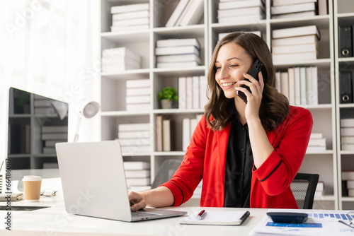 Happy young woman calling her friend talking and asking about something using laptop, middle aged business woman, female professional manager talking on the phone doing business on mobile phone